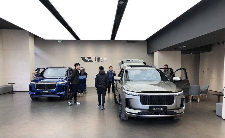 一侧为展车及休闲区,两辆 2020 款理想 one 展车停在展厅正中间,看车